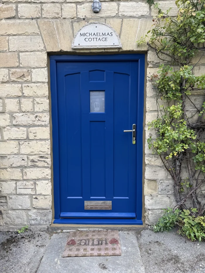 Blue panelled entrance door with a small glazed panel, silver-coloured lever handle and letterplate