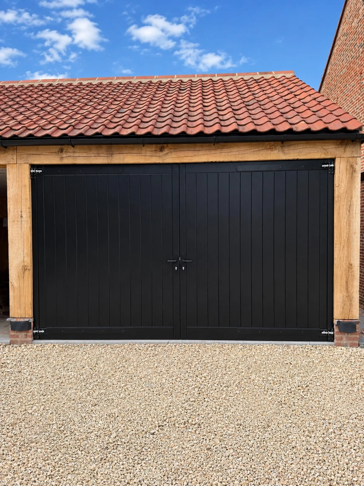 Black Accoya garage doors set in an oak cart-lodge frame, York
