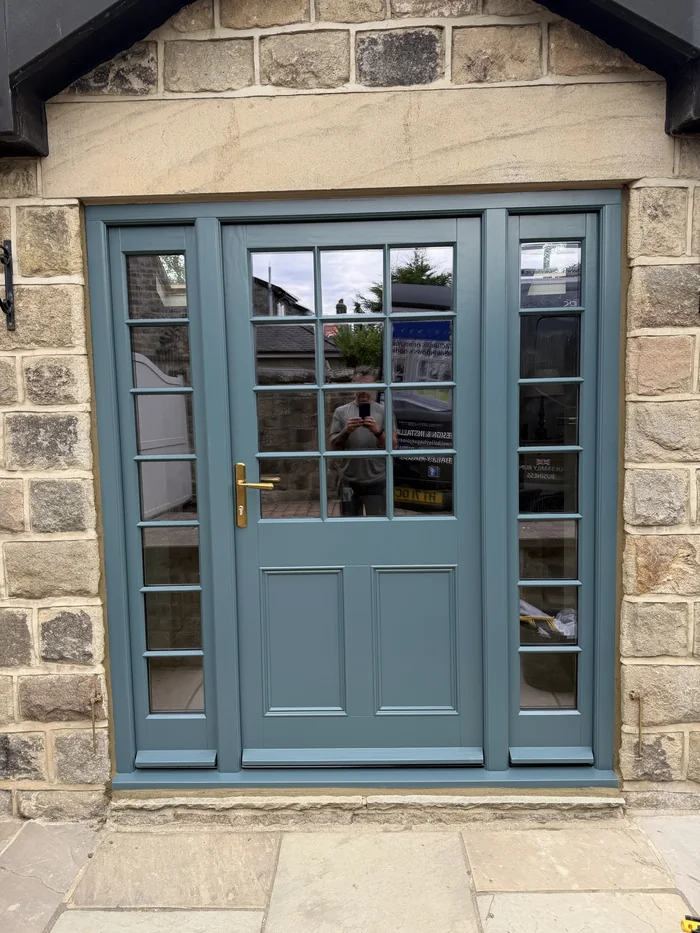 Grey-green glazed entrance door with matching sidelights and a brass-coloured lever handle