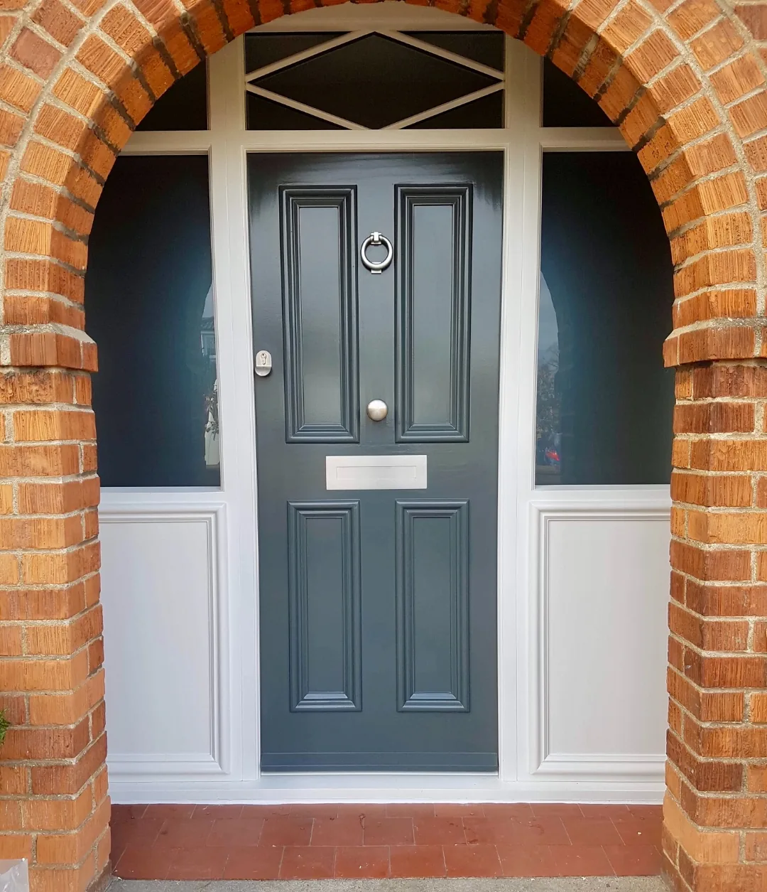 Charcoal grey heritage front door with sidelights and diamond transom in traditional brick arch — bespoke heritage door by Bailey Hague Joinery, York.