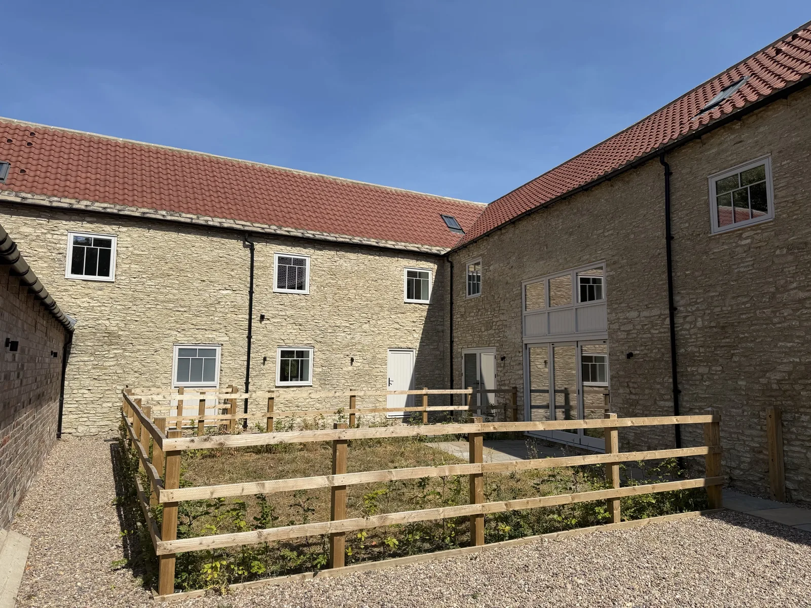 Two-storey stone barn conversion with hardwood casement windows and a fenced garden area
