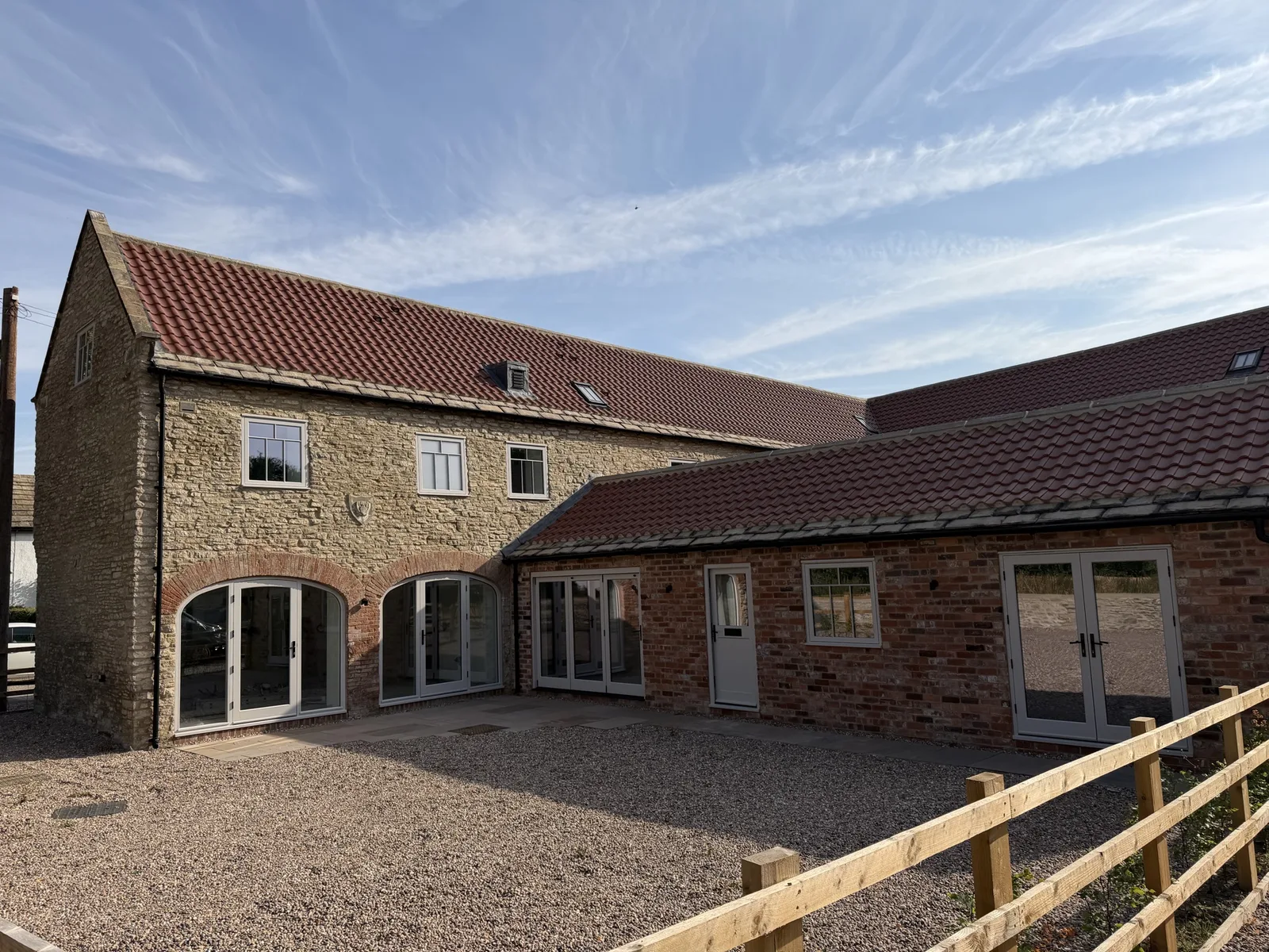Stone barn conversion courtyard with arched-head glazed hardwood doors, French doors and casement windows painted in a soft off-white