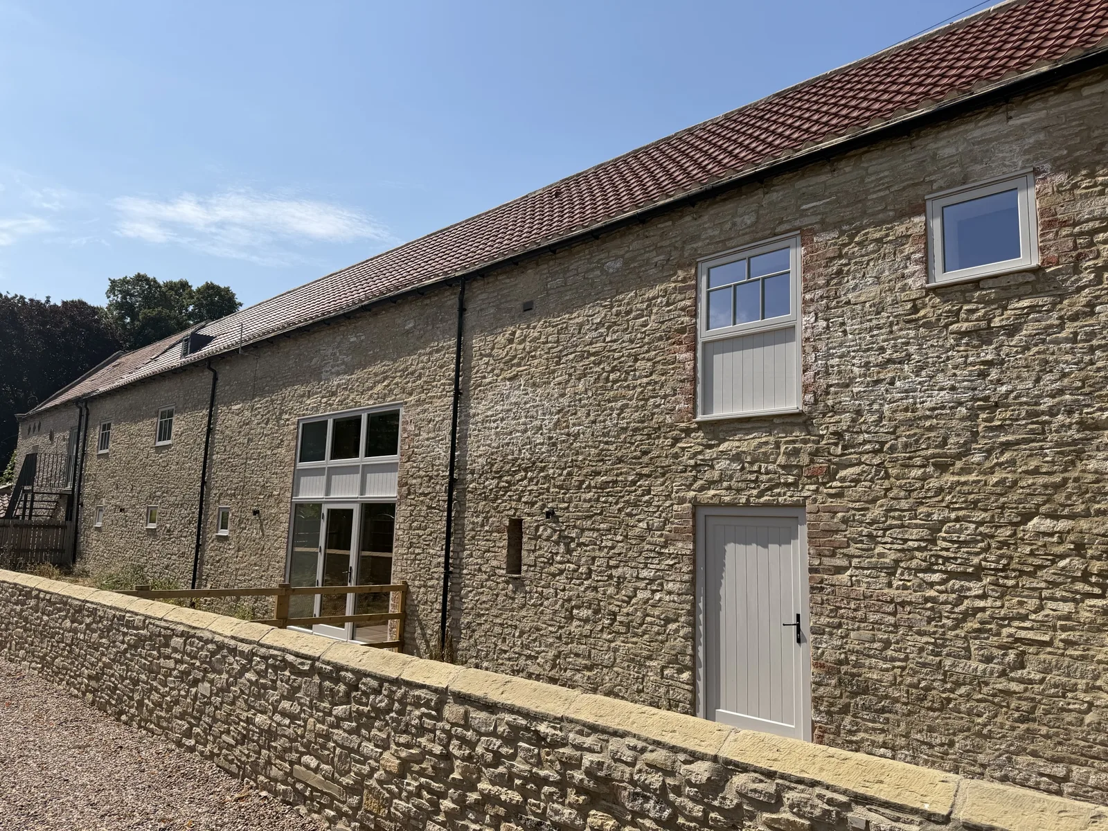 Stone barn elevation with a glazed screen, a boarded hardwood door and casement windows