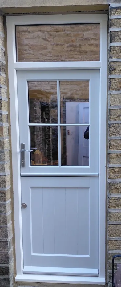Accoya pale grey stable door with a four-pane glazed top leaf, fanlight above, tongue-and-groove lower panel and a silver-coloured lever handle