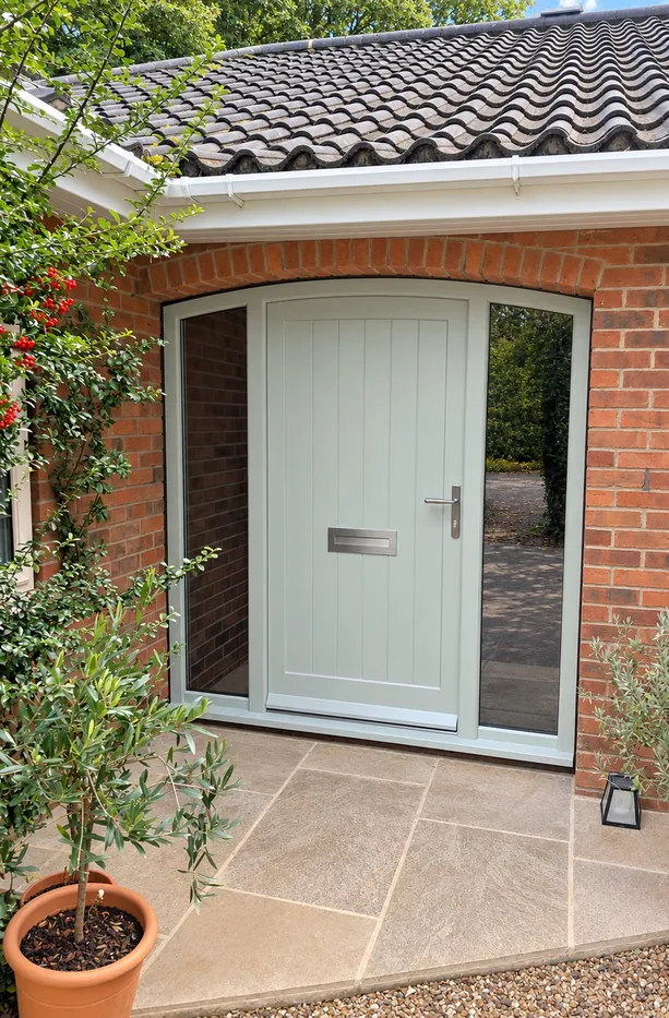 Accoya sage green vertically boarded front door in an arched frame with full-height glazed sidelights, stainless letterplate and lever handle, Bishopthorpe near York